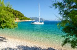 Una spiaggia da sogno nella penisola di Peljesac vicino a Trstenik (Croazia). Sullo sfondo, un'imbarcazione ormeggaita al largo della costa.
