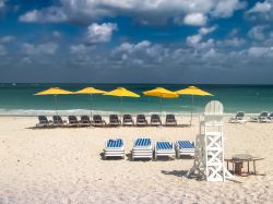 Una spiaggia di Bimini durante una giornata ventilata e nuvolosa, Bahamas. Sdraio e ombrelloni attendono i turisti che qui trovano un vero paradiso naturale dove rilassarsi e praticare attività ...