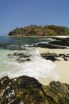 Una spiaggia rocciosa a Contadora Island, Panama, con la foresta sullo sfondo. Il versante meridionale dell'isola è caratterizzato dalla presenza di foreste selvagge che, diradandosi, ...