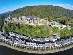 Una splendida fotografia aerea del maniero medievale di Bouillon, provincia del Lussemburgo (Belgio). Lungo le sponde del fiume Semois si affacciano le tipiche case dai tetti grigi.

