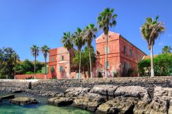 Una strada con case rosse lungo la costa dell'isola di Gorée, Dakar, Senegal. Classificata come patrimonio Unesco, quest'isola situata di fronte alla città di Dakar ospita ...