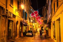 Una stretta stradina di Reggio Emilia, Emilia Romagna, fotografata di notte. A creare atmosfera, le decorazioni luminose a forma di ombrello.


