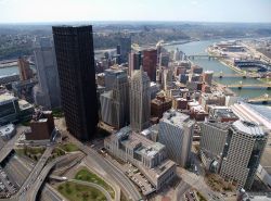 Una suggestiva veduta aerea della città di Pittsburgh, Pennsylvania, in una giornata di sole: grattacieli e edifici storici con il fiume Ohio sullo sfondo.

