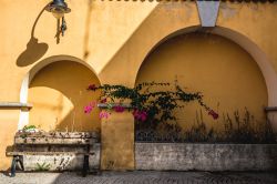 Una tipica costruzione all'interno di un cortile a Arbus, Sardegna. La facciata color giallo ocra di un vecchio edificio di Arbus con una panchina in legno.


