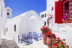 Una tipica stradina greca sull'isola di Amorgo, Grecia, con tavolini e sedie azzurre.



