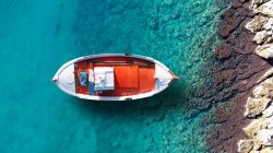 Una tradizionale barchetta da pesca nel porto di Schinoussa (Cicladi) con l'acqua azzurra e cristallina, Grecia.

