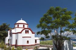 Una tradizionale chiesa greca a Mandraki, isola di Nisyros, Grecia, immersa nella vegetazione.

