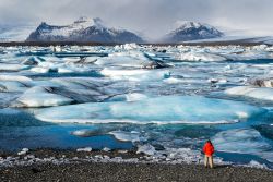 Una turista ammira lo spettacolare panorama offerto dalla laguna di Jokulsarlon, Islanda.
