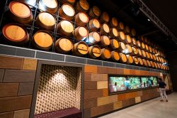 Una turista in visita al National Wine Centre of Australia di Adelaide: in questa sala, botti in legno per il vino e display con informazioni - © Keitma / Shutterstock.com