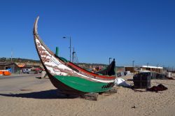 Una vecchia barca da pesca in legno sulla spiaggia di Costa da Caparica, Portogallo. In questa località dedita alla pesca si possono assaporare molti piatti a base di pesce, in particolare ...