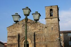 Una vecchia lampada da strada con la chiesa di Barcelos sullo sfondo, distretto di Braga, Portogallo.

