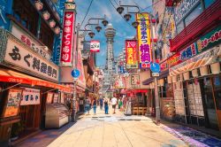 Una via pedonale di Osaka, Giappone, con negozi e attività commerciali. Sullo sfondo, la Tsutenkaku Tower - © YUSHENG HSU / Shutterstock.com