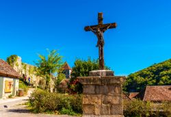 Uno scorcio del borgo francese di Saint-Cirq-Lapopie in Occitania. Una suggestiva croce con Gesù scolpito nella piazzetta del villaggio medievale.
