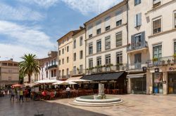 Uno scorcio del centro di Nimes con ristoranti all'aperto e gente a passeggio, Francia. L'emblema della città è il coccodrillo che rappresenta l'Egitto e la palma che ...