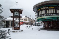 Uno scorcio del centro storico di Chamonix in inverno con la neve (Francia): la piazza centrale, l'orologio e i caffé di uno dei resort sciistici più antichi delle Alpi francesi ...
