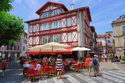 Uno scorcio del centro storico di Saint-Jean-de-Luz con gente a passeggio e in relax nei caffé all'aperto (Francia) - © EQRoy / Shutterstock.com