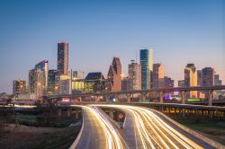 Uno scorcio dell'autostrada di Houston, Texas, al crepuscolo. Sullo sfondo, i grattacieli cittadini illuminati di sera.
