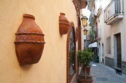 Vasi in terracotta sui muri di una casa nei vicoli di Castelmola, Sicilia. Lungo le strette viuzze di questo villaggio siciliano si affacciano belle abitazioni dall'architettura semplice ...