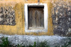 Un vecchio muro color giallo senape con persione in legno in un'abitazione di Othoni, Grecia.


