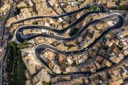 Veduta aerea del borgo storico di Ragusa con una strada a tornanti che serpeggia tra le case