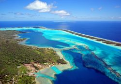 Veduta aerea della laguna di Bora Bora (Isole della Società, Polinesia Francese): la forma dell'isola è davvero originale, circondata dalla laguna a sua volta racchiusa dal ...