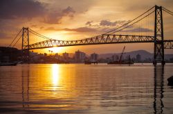 Veduta dell'Hercilio Luz Bridge a Florianopolis, Brasile, con il tramonto. Costruito a partire dal1920, venen inaugurato e aperto al traffico nel 1926. Questo ponte sospeso si estende per ...