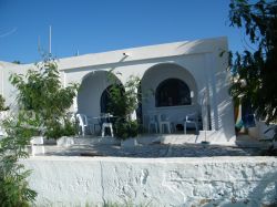 Veduta di una casa estiva a Maamoura, nei pressi di Nabeul, Tunisia. A fare da cornice al bianco dell'intonaco sono l'azzurro di porte e finestre e il verde della vegetazione.

