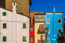 Veduta fotografica di una strada con le sue case dalle facciate variopinte a Chioggia, Veneto, Italia.
