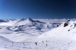 Veduta invernale sulla vetta del resort Les Arcs (Francia) con sciatori sulle piste.

