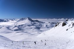Veduta invernale sulla vetta del resort Les Arcs (Francia) con sciatori sulle piste.

