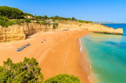 Veduta panoramica di una splendida spiaggia di sabbia lambita da acque cristalline nel villaggio di Armacao de Pera, Portogallo.
