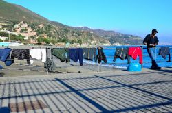 Venditori africani con prodotti sul lungomare di Arenzano, Liguria, in una giornata di sole.
