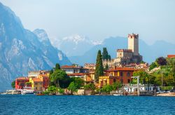 La città di Malcesine affacciata sul Garda, Veneto. Il castello e la torre cittadina con le montagne innevate sullo sfondo e le tipiche case colorate che si affacciano sul lago.



 ...