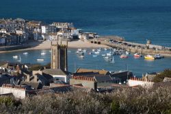 Vista sulla città vecchia e sul porto con le barche ancorate durante l'alta marea a St. Ives, Cornovaglia, Regno Unito. In primo piano la chiesa in un soleggiato pomeriggio di primavera ...