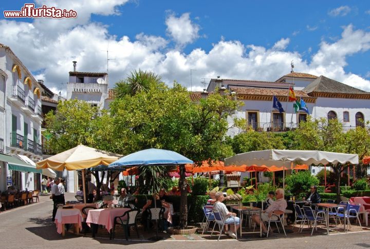 Immagine Turisti in relax ai caffé in Plaza de los Naranjos a Marbella, Spagna. Circondata da tipiche case andaluse bianche e da edifici storici, questa bella piazza ospita al suo centro una fontana in stile rinascimentale circondata da alberi di arancio piantati nel 1941 da cui l'area urbana prende per l'appunto il proprio nome - © Arena Photo UK / Shutterstock.com