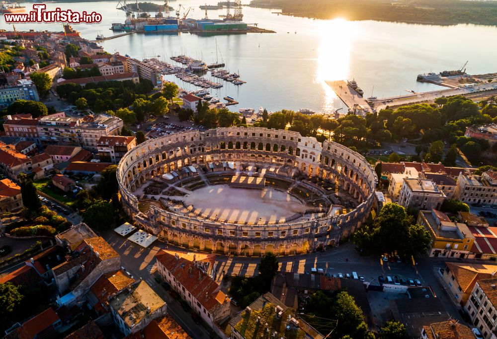 Immagine Pola, l'arena fotografata al tramonto dall'alto, Croazia. In pietra calcarea bianca, si presenta in tre ordini grazie alla sovrapposizione di due serie di archi. Vista dal litorale ha un'altezza di 32.5 metri dato che la costruzione sorge su un pendio.