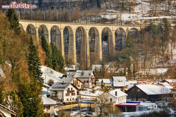 Immagine Il ponte della ferrovia incombe sulle case del borgo di Saint-Ursanne in Svizzera, imbiancato dopo una nevicata invernale - © SilvanBachmann / Shutterstock.com