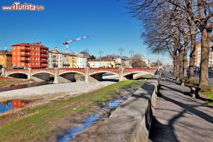 Immagine Il Ponte di Mezzo a Parma: un passaggio sull'antica via Emilia - Il Ponte di Mezzo, tra i più antichi della città, fu costruito verso la fine del XII secolo come passaggio sul torrente Parma, nel percorso della storica via Emilia, l'antica strada romana che collegava Rimini e Piacenza. Un ponte di antica costruzione dunque, che permette il passaggio tra le due parti della città divise dalla Parma e che svetta nella sua storicità in confronto agli edifici moderni che sorgono nelle vicinanze. - © iryna1 / Shutterstock.com