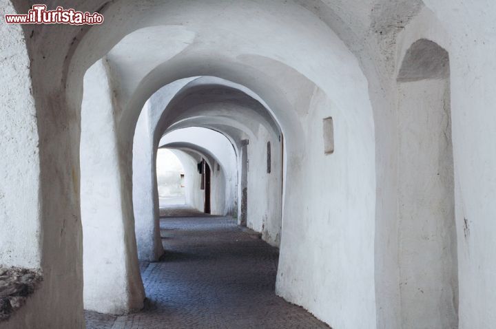 Immagine Portico nel borgo di Glorenza, Trentino Aldo Adige. All'interno della mura il paese è un susseguirsi di scorci molto suggestivi con torri e portici ed una piazza centrale, Stadt Platz, caratterizzata da una fontana e sulla quale si affacciano edifici di varie forme e stili. Su alcune porte della cinta muraria sono ancora visibili dei motti e delle scritte risalenti all'epoca fascista - © Claudio Giovanni Colombo / Shutterstock.com