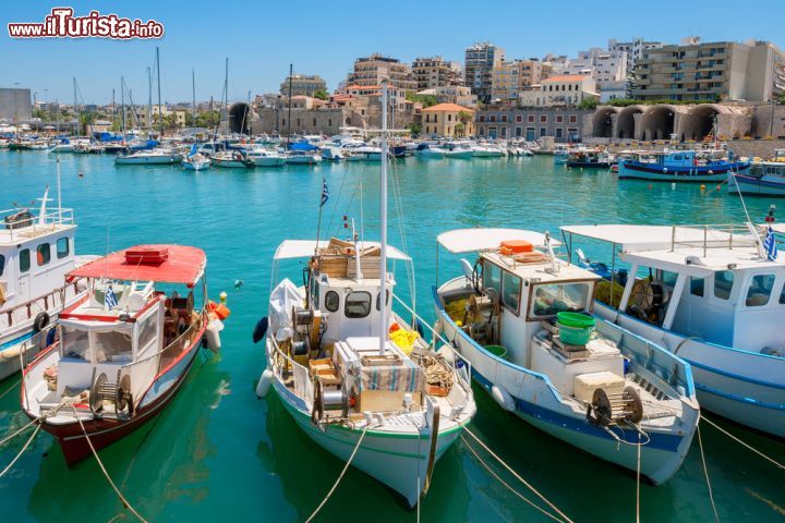Immagine Porto di Heraklion, Creta - Le barche ormeggiate nel porto della città con sullo sfondo case e abitazioni che si affacciano sulle acque del Mar Mediterraneo: Heraklion è oggi un mix di quartieri moderni, piazze raccolte, edifici antichi, strade tortuose e ricordi storici © Andrei Nekrassov / Shutterstock.com