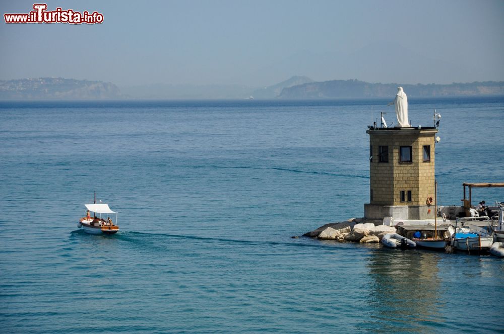 Immagine Il porto di Procida con barche e la statua bianca di Santa Maria, baia di Napoli, Campania.