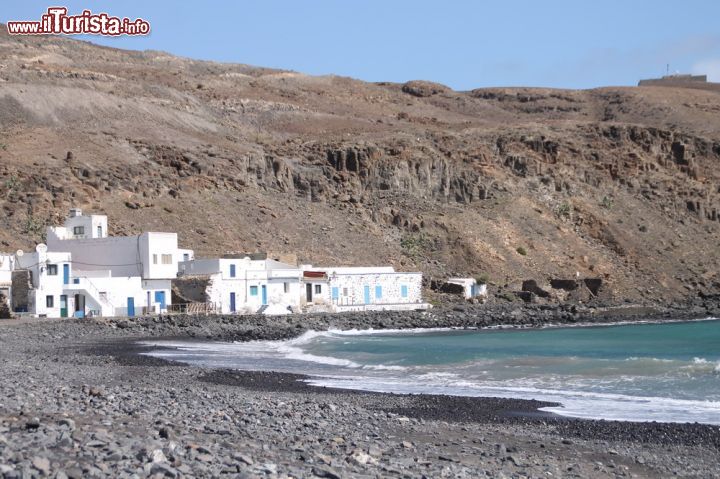 Immagine Pozo Negro, Fuerteventura, Spagna - Sono solo una decina o poco più le casette che si possono trovare in questa parte sita a sud di Caleta de Fuste, denominata la baia di Pozo Negro. Le pochissime abitazioni rendono l'idea della tranquillità che si può respirare qui, per questo rappresenta il luogo ideale delle famiglie e dei romantici. I limitati insediamenti urbani risalgono al fatto che questo sito è di orgine vulcanica, ragion per cui è molto apprezzato dai naturalisti.