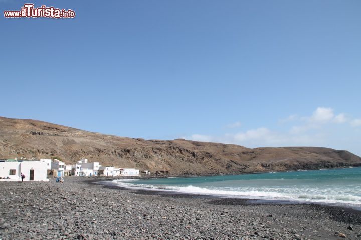 Immagine Litorale della spiaggia di Pozo Negro, Fuerteventura (Spagna) - La spiaggia di Pozo Negro si trova accanto a quella di El Muellito e si estende nella parte meridionale di Caleta de Fuste. Il suo nome deriva dal villaggio dei pescatori da cui ha origine. Come si può vedere dall'immagine il suo fascino è dato soprattutto dall'ambiente circostante, che richiama alla sua origine vulcanica. Per questo motivo rappresenta un fiore all'occhiello della tradizione del posto e grazie alla sua natura selvaggia, libera e incontaminata, attrae tutti gli amanti delle escursioni.