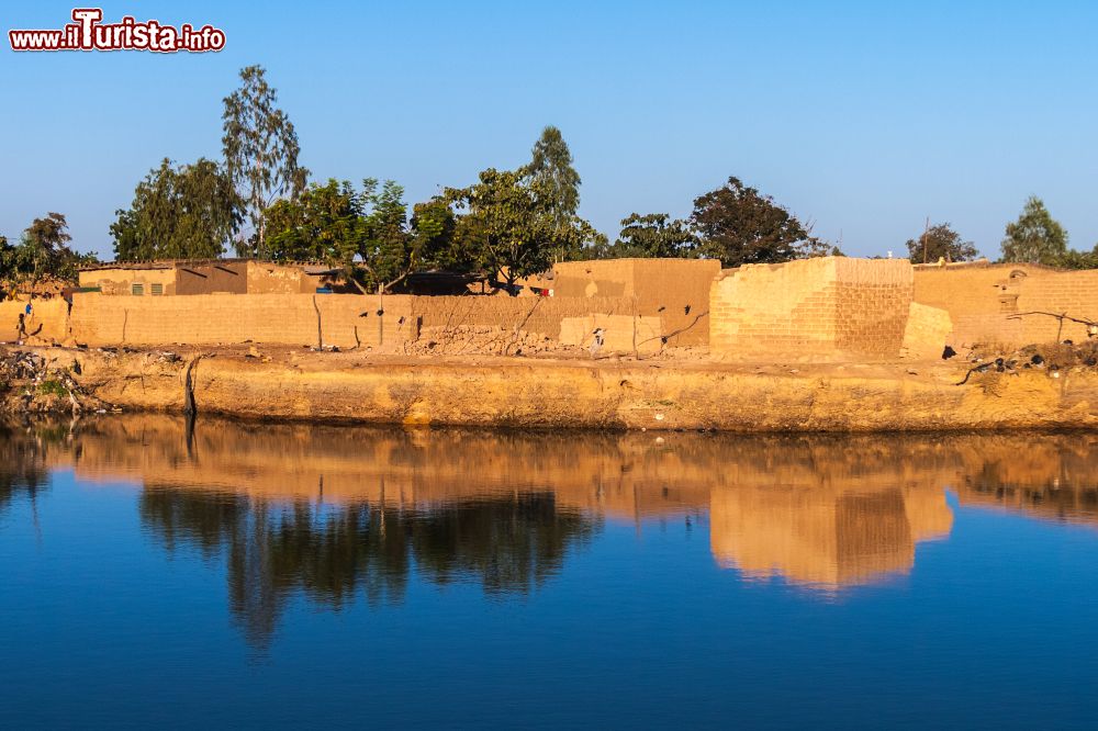 Immagine Quartiere orientale di Ouagadougou in una giornata di sole, Burkina Faso (Africa). Le costruzioni in mattoni di fango si rispecchiano nella grande pozza d'acqua in pirmo piano.