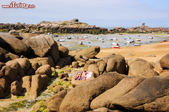 Immagine Ragazze prendono il sole sulle rocce di Ploumanac'h, Francia. Sullo sfondo, barche con la bassa marea 