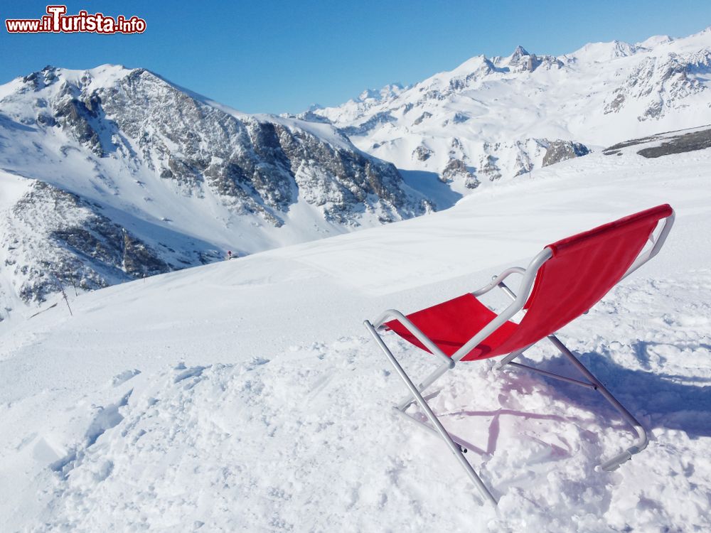 Immagine Relax su una sdraio rossa sulle piste innevate di Valfrejus, Francia. Questo comprensorio sciistico si sviluppa fra i 1550 metri di altezza della stazione a valle ai 2737 degli impianti in quota.