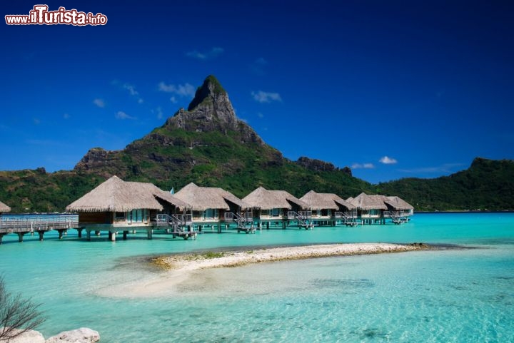 Immagine Resort di lusso sull'isola di Bora Bora, il gioiello della Polinesia Francese, con la sagoma del monte Otemanu sullo sfondo. Si tratta in realtà di un vulcano spento, alto circa 700 metri e ricoperto di florida vegetazione tropicale - © bl0ndie / Shutterstock.com