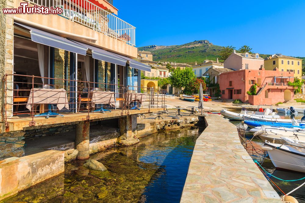 Immagine Ristorante al porto di Erbalunga, Corsica, Francia. Si affaccia sulle acque del mare di Corsica questo grazioso ristorante fotografato in una soleggiata mattina estiva.