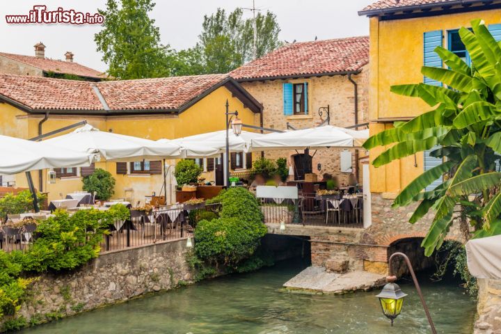 Immagine Ristorante a Borghetto sul Mincio, Verona - Burro e salvia ma anche in brodo. Si possono gustare così i celebri tortellini di Valeggio e Borghetto sul Mincio che qui si chiamano "nodo d'amore" perchè ricorderebbero il nodo di un fazzoletto di seta intrecciato da due amanti prima di gettarsi nelle acque del fiume Mincio. In questa immagine uno dei ristoranti tipici del villaggio © GoneWithTheWind / Shutterstock.com