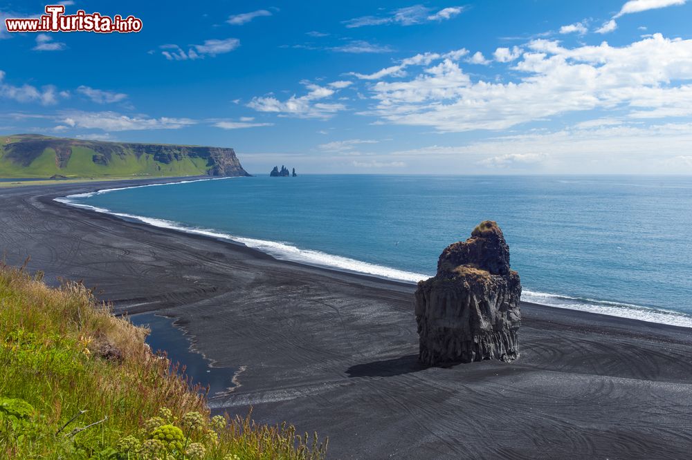 Immagine Rocce a Cape Dyrholaey, il punto più a sud dell'Islanda. La sabbia nera della spiaggia contrasta l'azzurro del mare  e il verde splendente della vegetazione.
